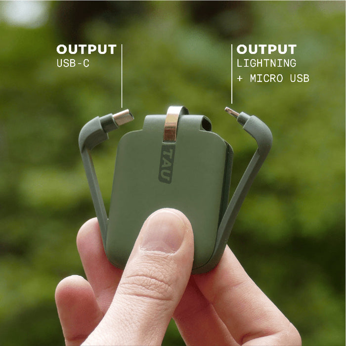 TAU® - Always-charged power bank - Charcoal Black - Compact agave green power bank with built-in USB-C, Lightning, and Micro USB cables held in hand outdoors. - Rolling Square